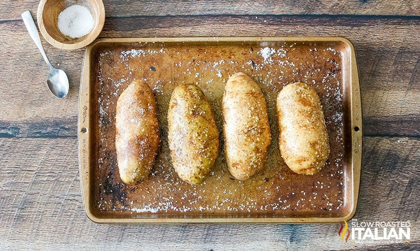 4 russet potatoes coated in oil and salt on baking sheet