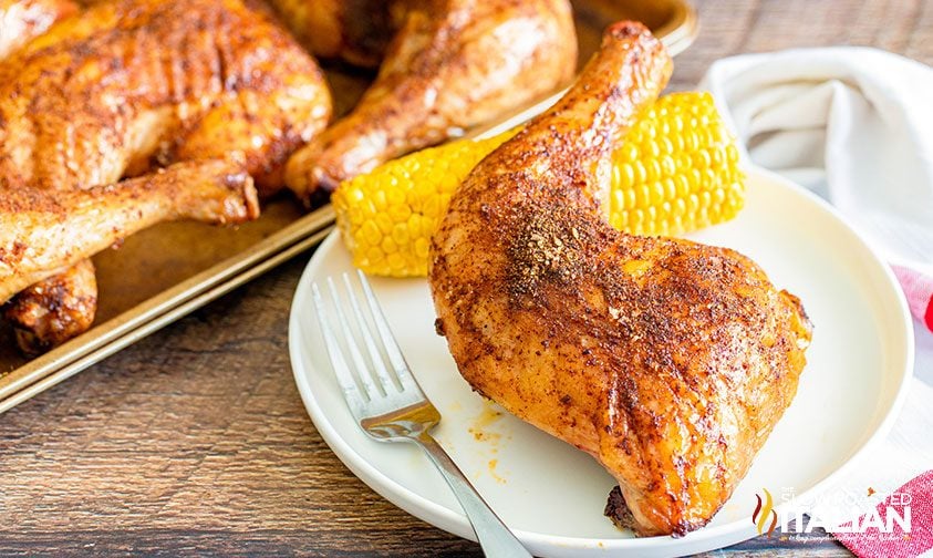 smoked chicken quarter and corn on the cob on a plate