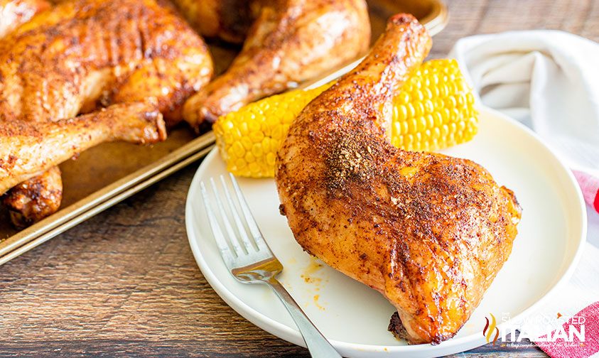 smoked chicken quarter and corn on the cob on a plate