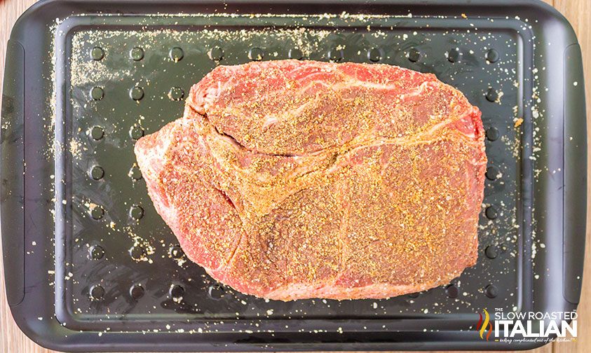 chuck roast coated in dry rub on a smoking tray