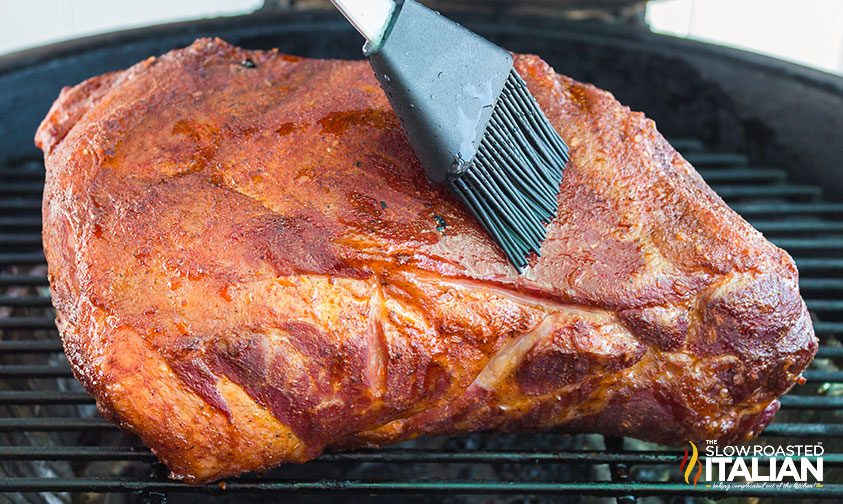 brushing pineapple juice over smoked pork shoulder