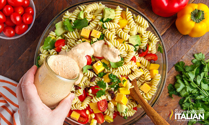 pouring chipotle ranch dressing over pasta salad