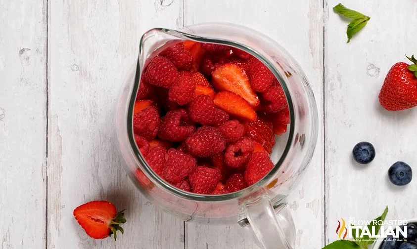 overhead: strawberries and raspberries in drink pitcher