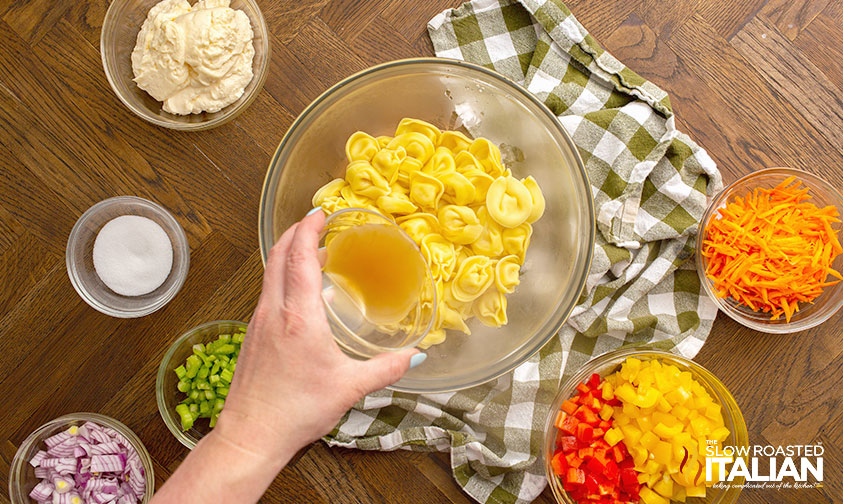 pouring apple cider vinegar over drained and cooked tortellini