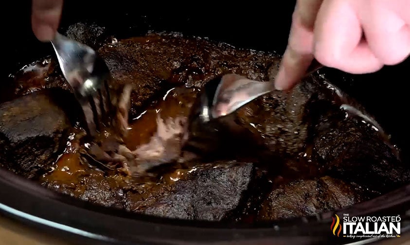 shredding beef in crockpot with two forks