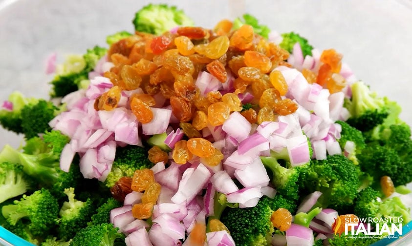 raisins, chopped onions and broccoli in a serving bowl