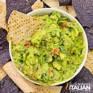 chunky guacamole in a white bowl with tortilla chips