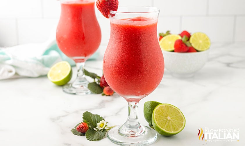 strawberry daiquiris in hurricane glass with fresh strawberry garnish