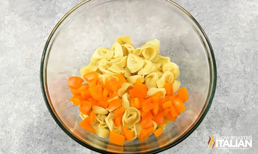 bowl of cooked tortellini and diced orange bell peppers