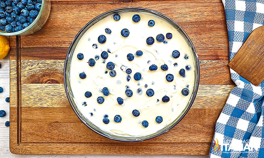 overhead: lemon blueberry cheesecake on wooden cutting board