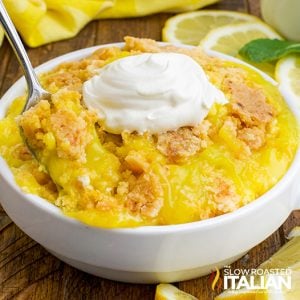 bowl of lemon dump cake with a dollop of whipped cream