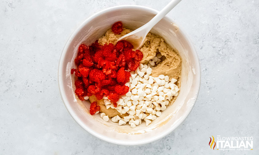 adding raspberries and white chocolate chips to cookie dough