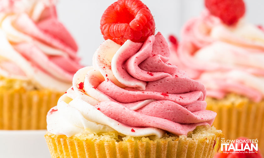closeup of swirled icing and fresh raspberry on raspberry cupcakes