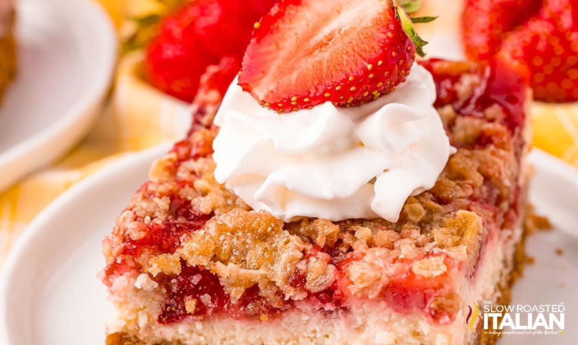 strawberry cheesecake bar with a dollop of whipped cream and a fresh strawberry