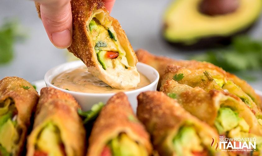 dipping avocado eggroll in chipotle ranch sauce