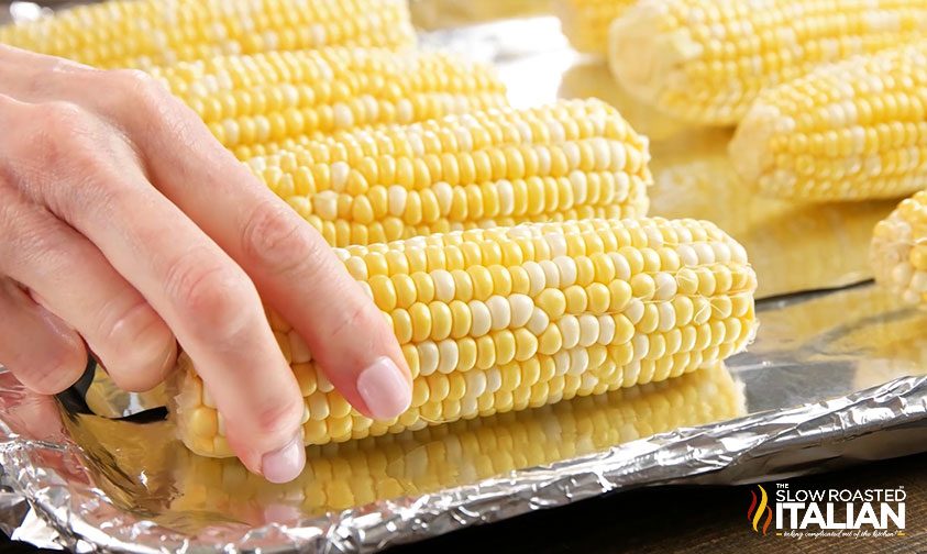 placing corn on the cob on a foil lined sheet pan