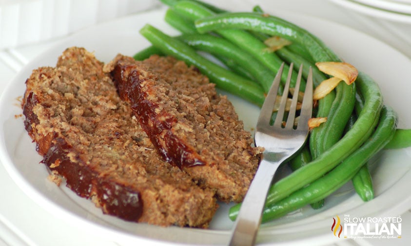 slices of meatloaf on plate with green beans
