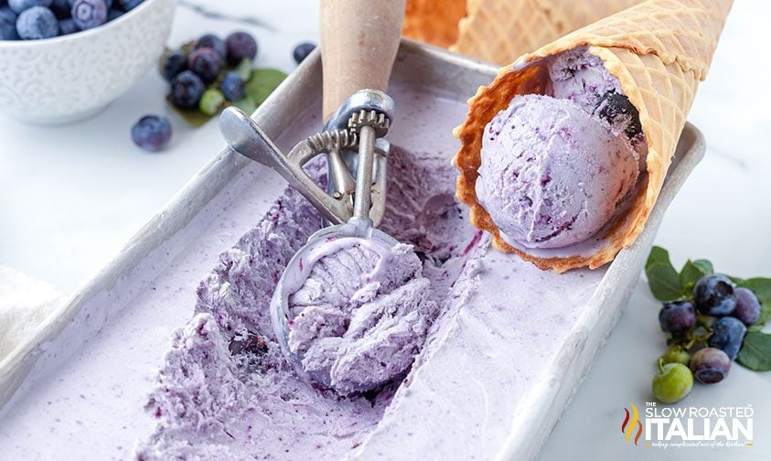 blueberry ice cream scooped from pan and in waffle cone