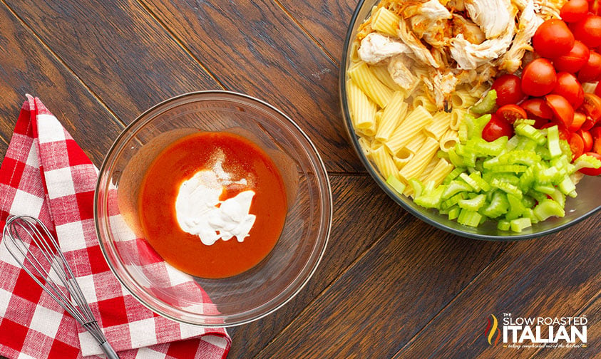 bowl of buffalo sauce and ranch dressing next to larger bowl of salad ingredients