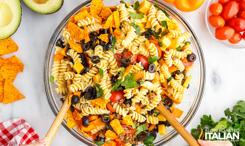 tossing taco salad with pasta using wooden spoons