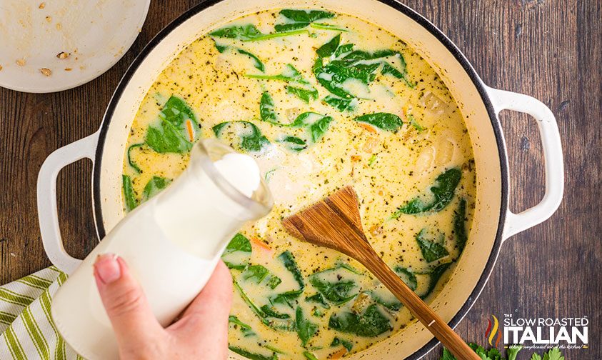 pouring cream into chicken gnocchi soup with spinach