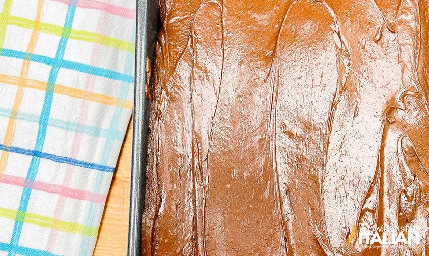 frosting fudge cake in metal pan