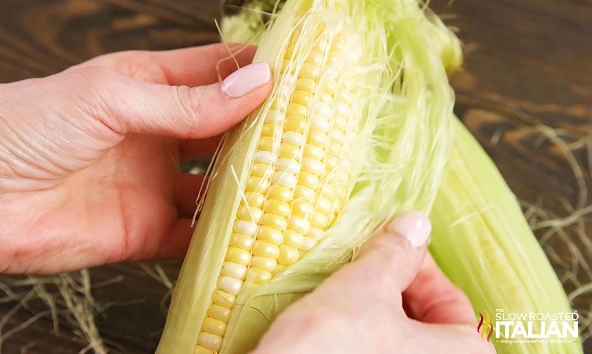 husking an ear of corn