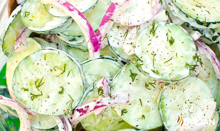 sliced cucumbers and red onion with dill and creamy dressing