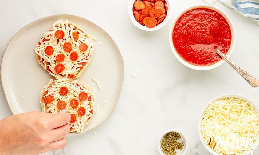 placing mini pepperoni on english muffin pizzas