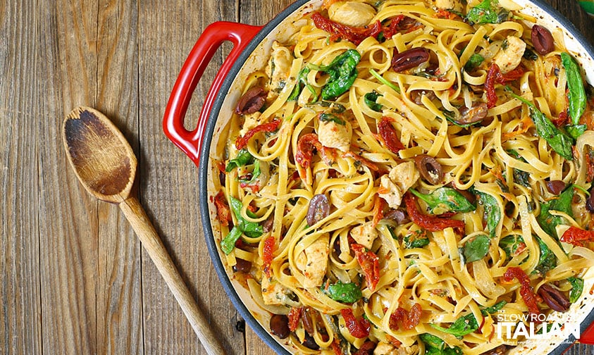 overhead: wide pot of greek chicken pasta with wooden spoon