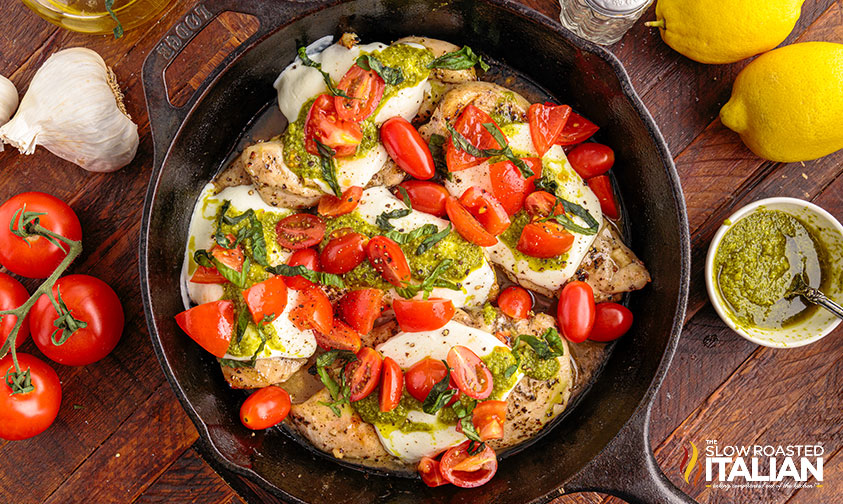 slice grape tomatoes over mozzarella pesto chicken in skillet