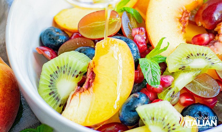 pouring honey lime dressing over peach salad