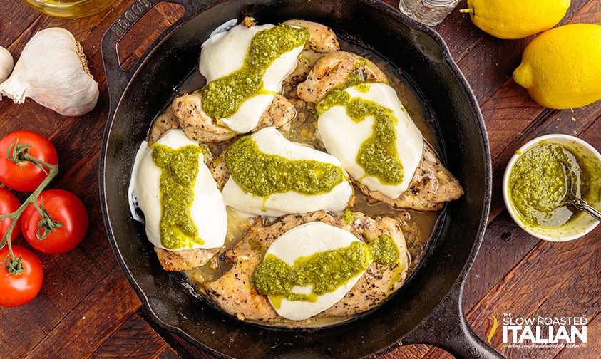 chicken topped with mozzarella and pesto in cast iron skillet