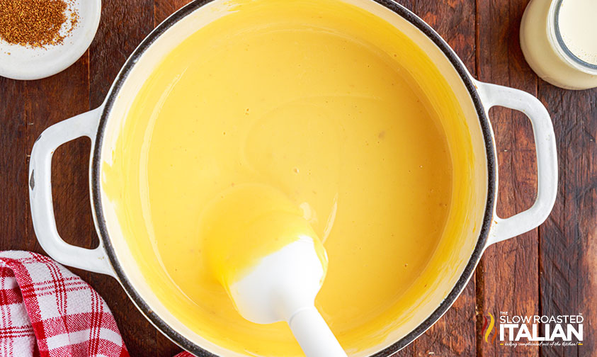 stirring homemade nacho cheese in pot