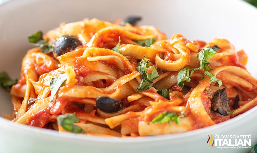 close up: pasta puttanesca in white bowl