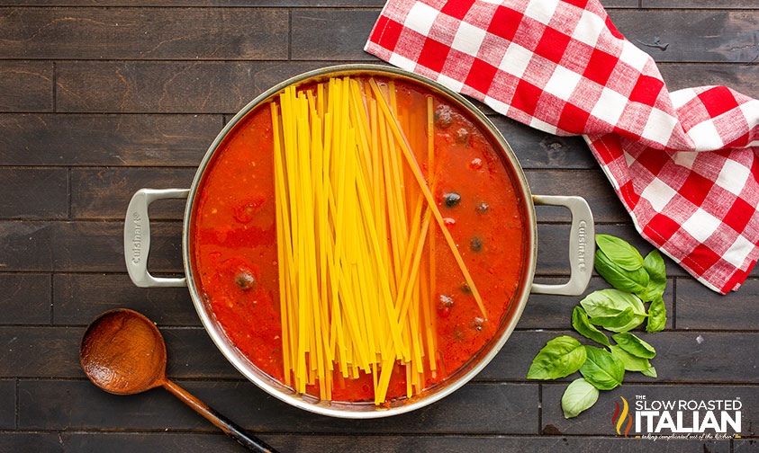 dry fettucine and puttanesca sauce in skillet