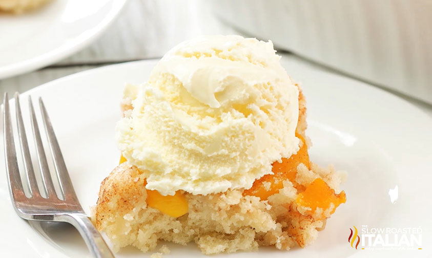 slice of peach dump cake topped with vanilla ice cream