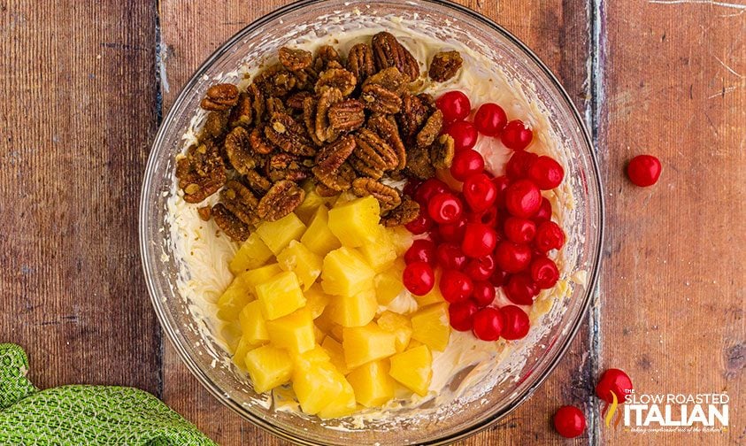 canned pineapple, maraschino cherries, and candied pecans over cheesecake mixture