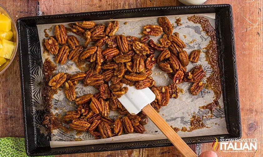 flipping candied pecans on sheet pan with spatula