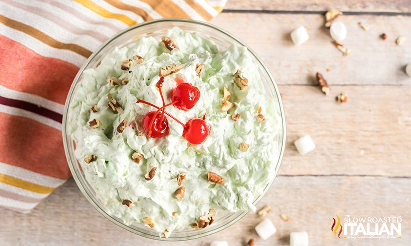 overhead: bowl of pistachio dessert salad topped with cherries