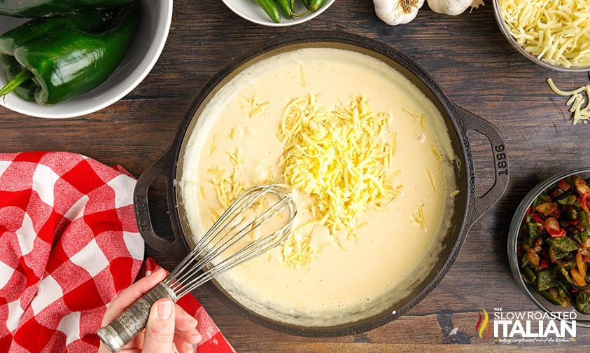 whisking shredded cheese into queso dip