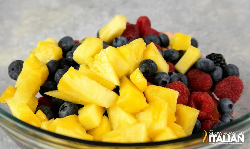 berries and chopped pineapple in glass bowl