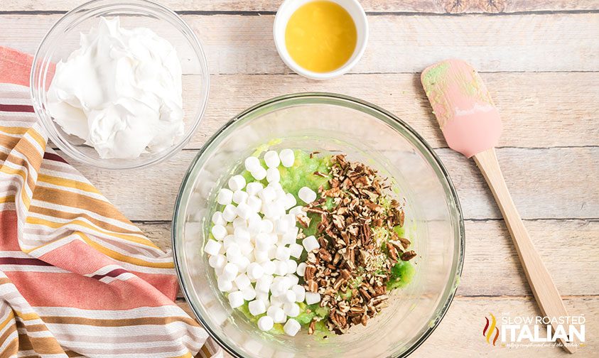 mini marshmallows and chopped pecans in bowl with pudding pineapple mixture