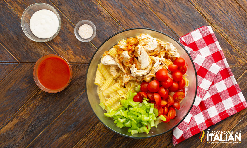 pasta, chicken, and veggies in bowl next to bowls of sauces