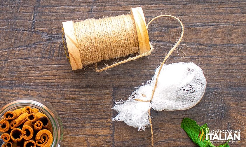 cheesecloth sachet of spices tied with twine attached to a spool