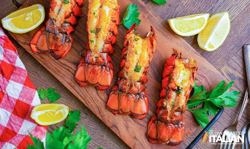 smoked lobster tails with lemon wedges on wooden board