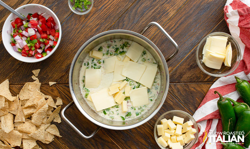 pieces of white cheese in pot with cream, onion, and peppers