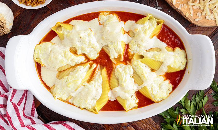 pan of stuffed italian shells over marinara topped with alfredo