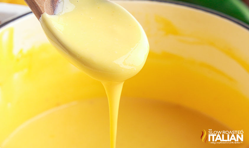 cheese sauce pouring off of spoon into pot