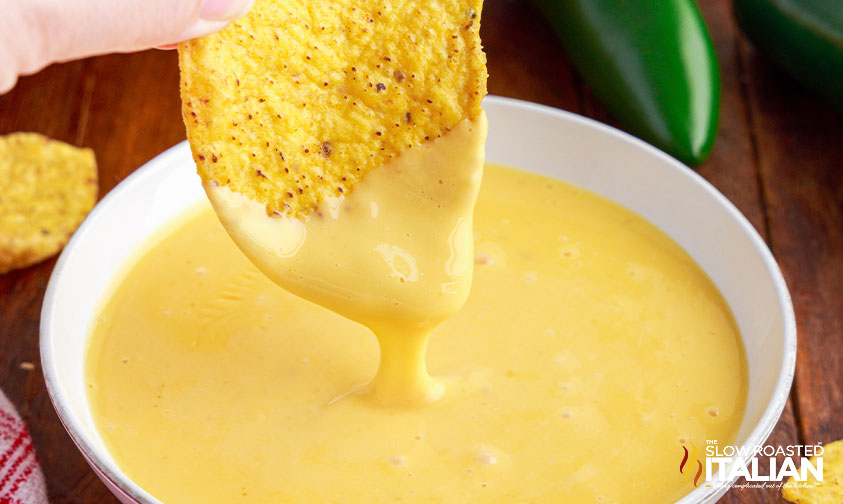 dipping tortilla chip in cheese sauce